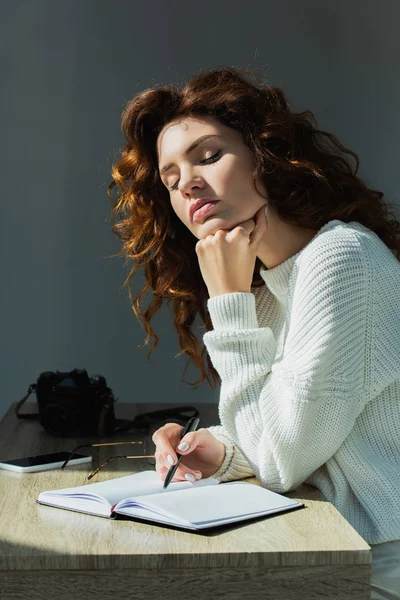 Curly Redhead Girl Closed Eyes Holding Pen Notebook While Sitting — Stock Photo, Image