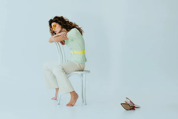 Curly Redhead Young Woman Yellow Sunglasses Sitting Chair Heels Grey — Stock Photo, Image