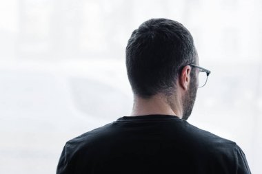 siyah t-shirt yetişkin depresif adam arka görünümü evde pencereden dışarı bakıyor