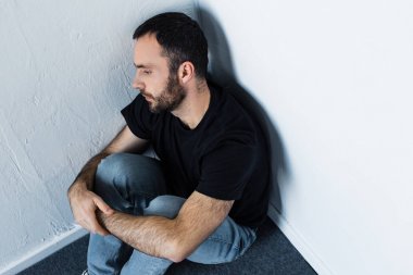 yakışıklı sakallı depresif adam köşede katta oturan ve uzağa bakıyor