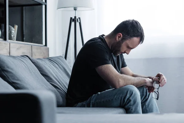 Hombre Deprimido Sosteniendo Gafas Mientras Está Sentado Sofá Gris Casa — Foto de Stock