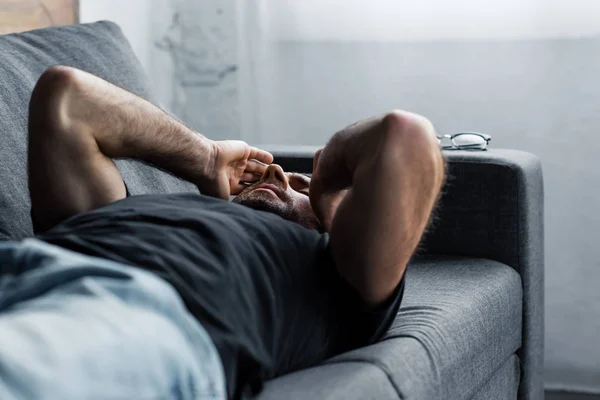 Depressed Man Lying Grey Sofa Closed Eyes Hands Head — Stock Photo, Image