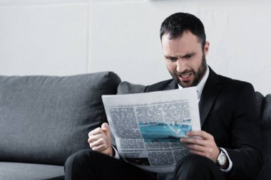 yakışıklı sinirli iş kanepede oturan ve gazete okuma