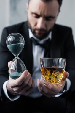 kum saati ve viski bardağı tutan üzgün işadamı seçici odak