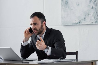 işyerinde otururken ve akıllı telefonda konuşurken öfkeli işadamı bağırıyor