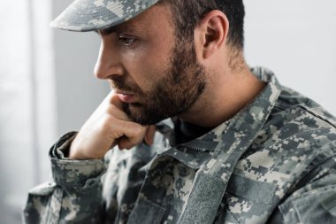 pensive bearded military man in uniform holding hand near face clipart