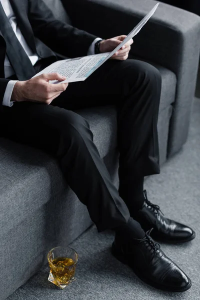 Geschäftsmann Sitzt Auf Sofa Mit Zeitung Neben Glas Whiskey Auf — Stockfoto