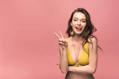pembe izole barış işareti gösteren sarı mayo güzel genç kadının ön görünümü