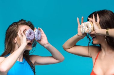 two girls in swimsuits holding donuts isolated on blue clipart