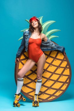 mayo ve paten li kadının tam boy görünümü mavi dekoratif ananas yakınında duruyor