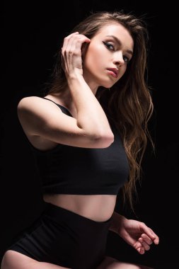 iç çamaşırı çekici genç kadın saç dokunmadan ve siyah izole kamera bakıyor