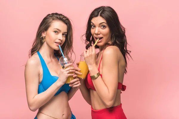 Twee Mooie Meisjes Bikini Drinken Sinaasappelsap Geïsoleerd Roze — Stockfoto