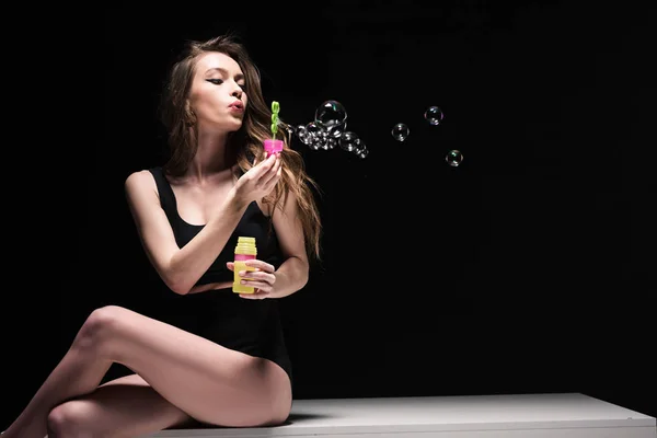 Pretty Young Woman Sitting Table Blowing Soap Bubbles Isolated Black — Stock Photo, Image