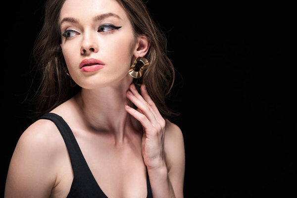 красивая девушка нежно касаясь шеи и глядя в сторону изолированы на черный
