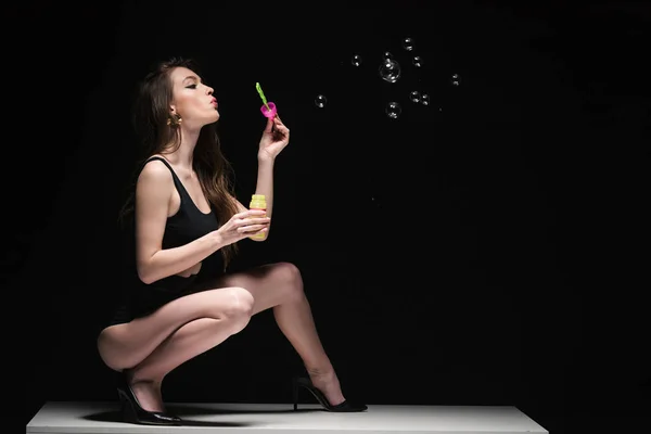 Pretty Young Woman Sitting Table Blowing Soap Bubbles Isolated Black — Stock Photo, Image