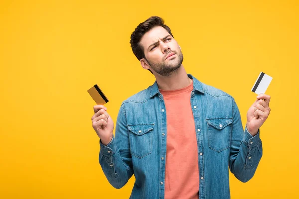 Homem Boa Aparência Confuso Segurando Cartões Crédito Isolados Amarelo — Fotografia de Stock