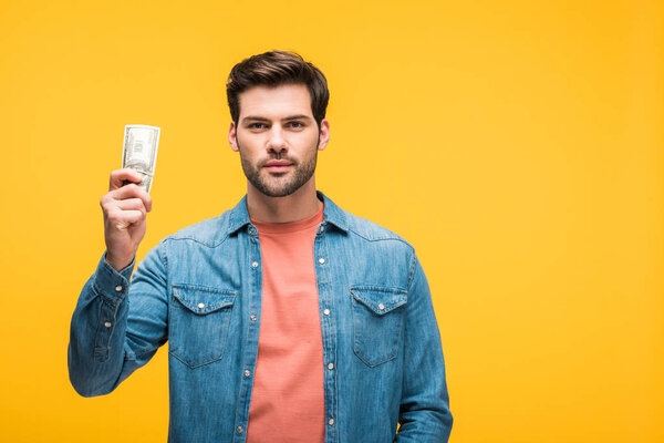 handsome man holding money isolated on yellow with copy space