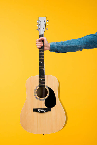 обрезанный вид человека, держащего акустическую гитару изолированной на желтом
