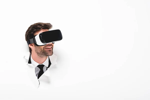 Homem Sorridente Realidade Virtual Fone Ouvido Atrás Buraco Parede Branco — Fotografia de Stock