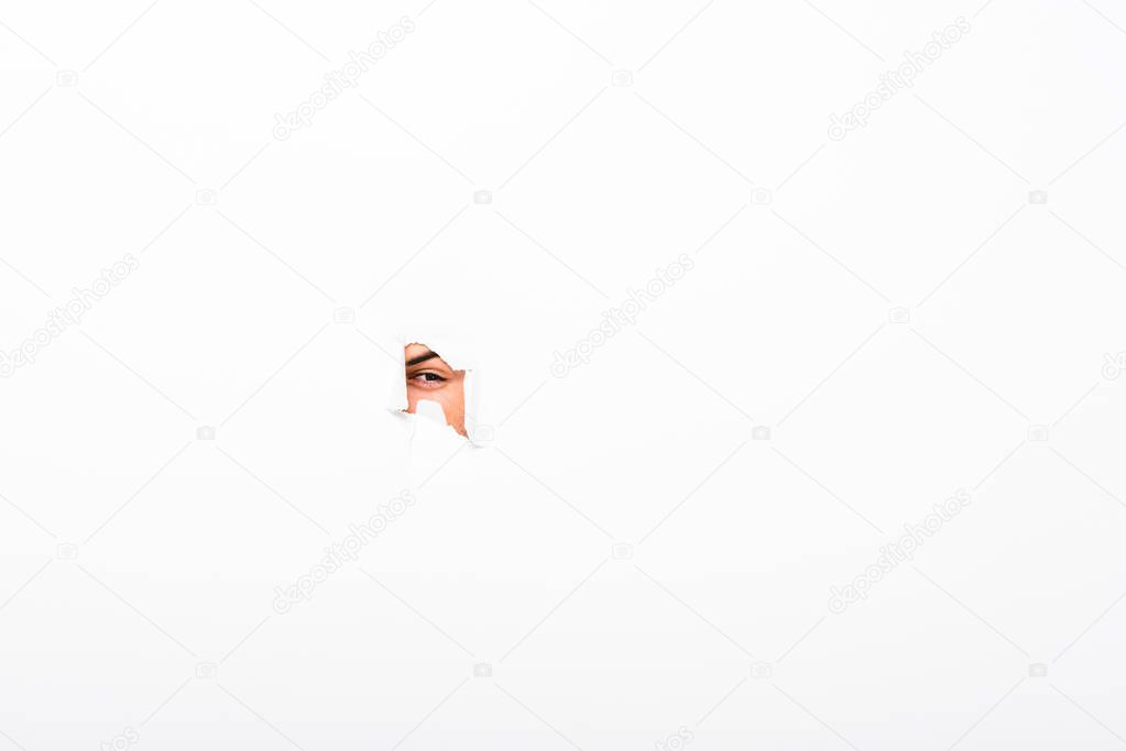 man looking out from hole in paper wall on white with copy space