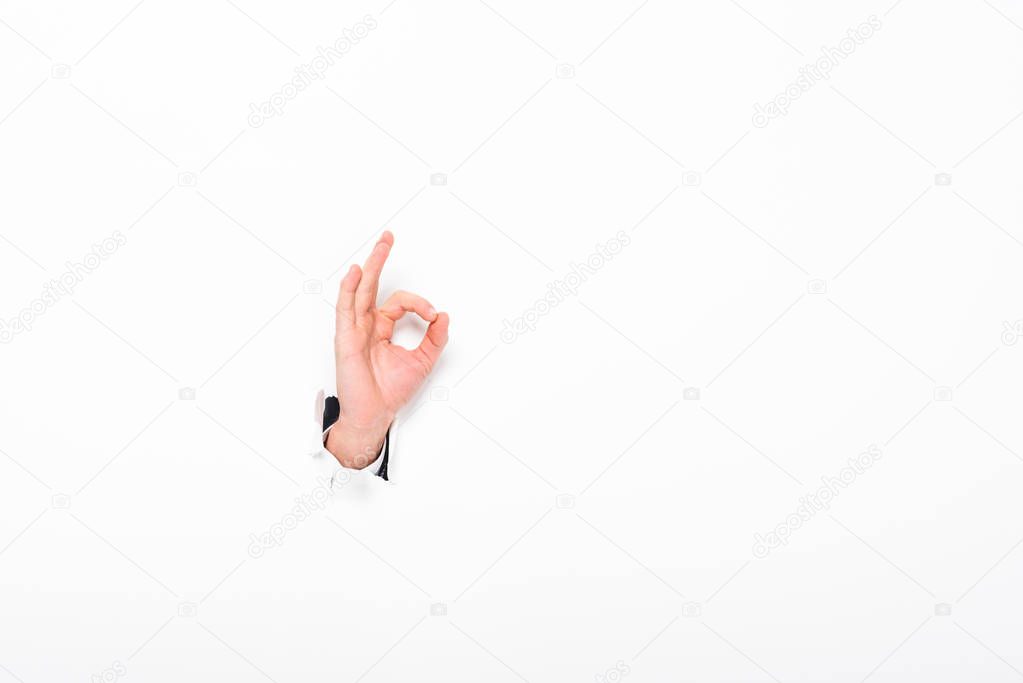 man showing ok sign from hole in paper wall on white with copy space
