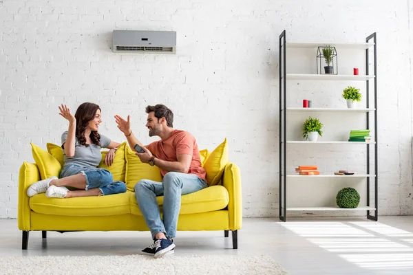 Fröhlicher Mann Und Frau Gespräch Auf Gelbem Sofa Unter Klimaanlage — Stockfoto