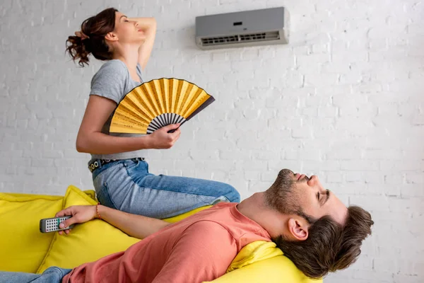 自宅で暑さに苦しむ手ファンを持つ目を閉じた男と女性を横たわって — ストック写真