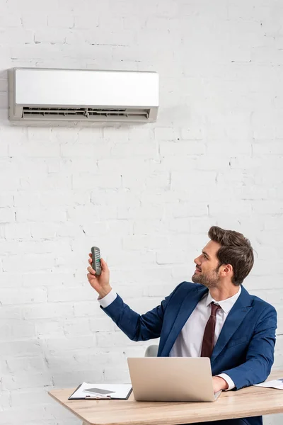 Handsome Businessman Holding Remote Control While Sitting Workplace Air Conditioner — Stock Photo, Image