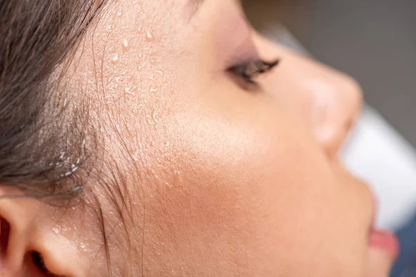 close up view of young woman with sweaty face suffering from heat on grey