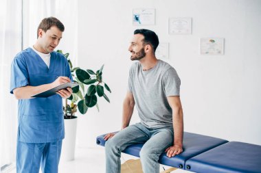 Masaj kabine klinikte Pano üzerinde reçete yazma koltuk ve Doktor oturan gülümseyen hasta