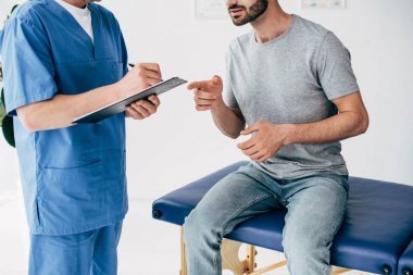 Pano ve hasta kanepede oturan ve klinikte masaj kabine parmak ile işaret Doktor yazma reçete kırpılmış görünümü