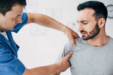 Hasta kanepede oturan seçici odak ve Doktor masaj dolabı klinikte hasta omuz Masaj