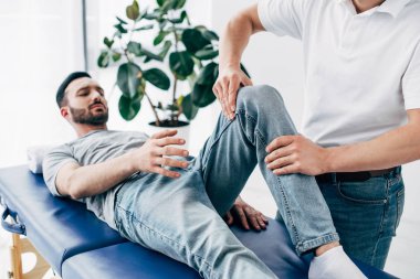 Hastane masaj masasında yatan hastanın fizyoterapist masaj bacak