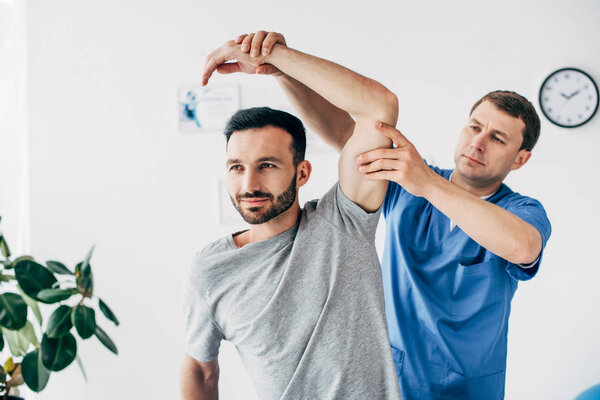 Хиропрактик протягивает руку красивого пациента в больнице
