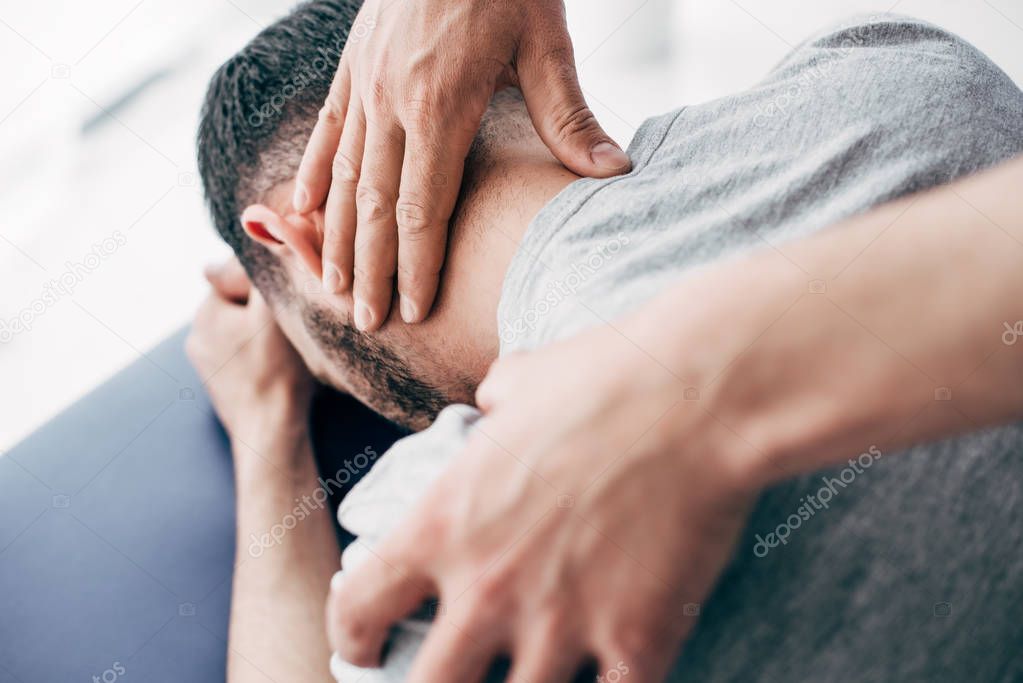 selective focus of chiropractor massaging neck of man in hospital