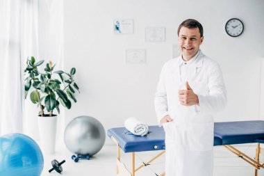 iyi görünümlü gülümseyen chiropractor hastanede başparmak kadar gösteren