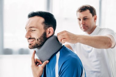 Hastanede boyun Brace gülümseyen futbol oyuncusu inceleyen chiropractor