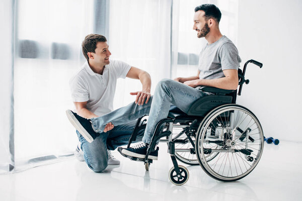 Улыбающийся физиотерапевт массирует ногу инвалида в инвалидном кресле
 