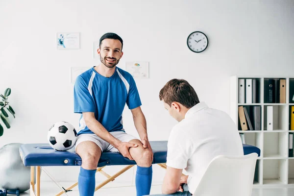 Fisioterapista Che Esamina Giocatore Calcio Sorridente Ospedale — Foto Stock