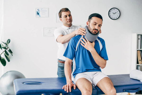 Хиропрактик осматривает футболиста в шейном корсете в больнице
