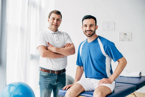 Glimlachend Fysiotherapeut Voetbalspeler Het Ziekenhuis Kijken Naar Camera — Stockfoto