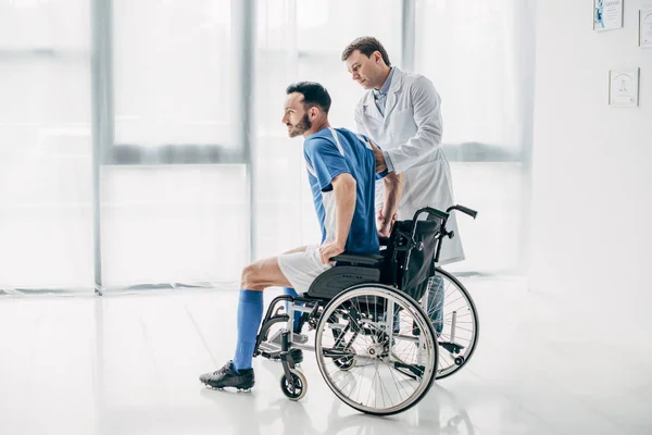 Physiotherapist helping handicapped football player in Wheelchair during recovery