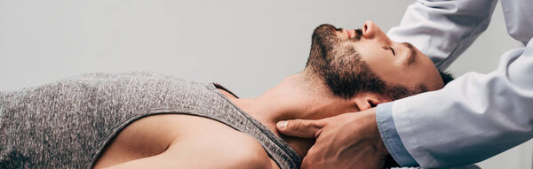 панорамный снимок хиропрактика, массирующего шею человека на сером
