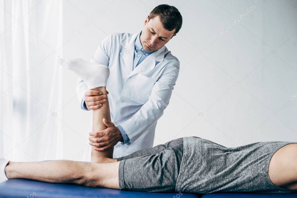 Physiotherapist stretching leg of patient in hospital