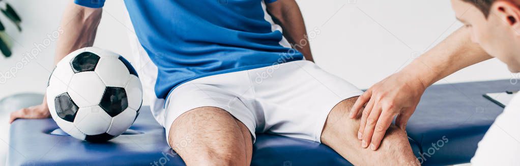 panoramic shot of Physiotherapist massaging leg of football player in hospital