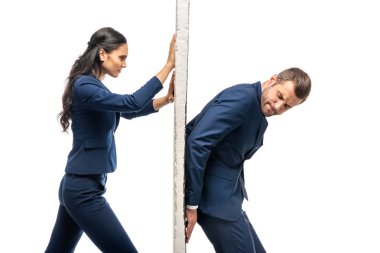 businessman and businesswoman in suits pushing wall isolated on white