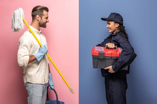 man in rubber gloves with mop and woman in construction worker uniform with tool box on blue and pink