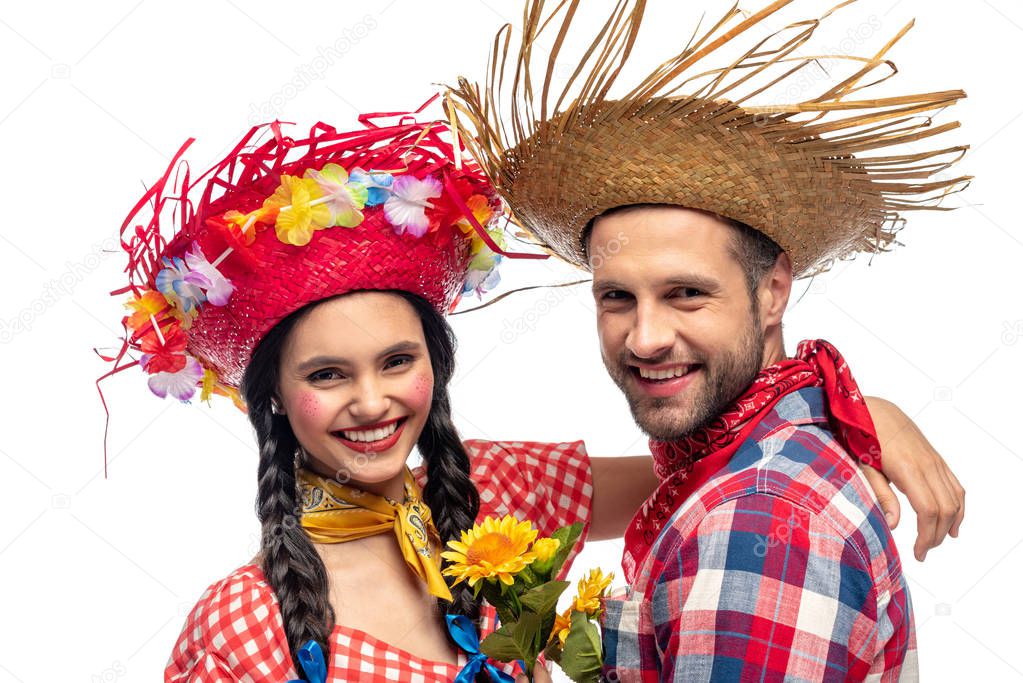 happy man and young woman in festive clothes with sunflowers looking at camera isolated on white