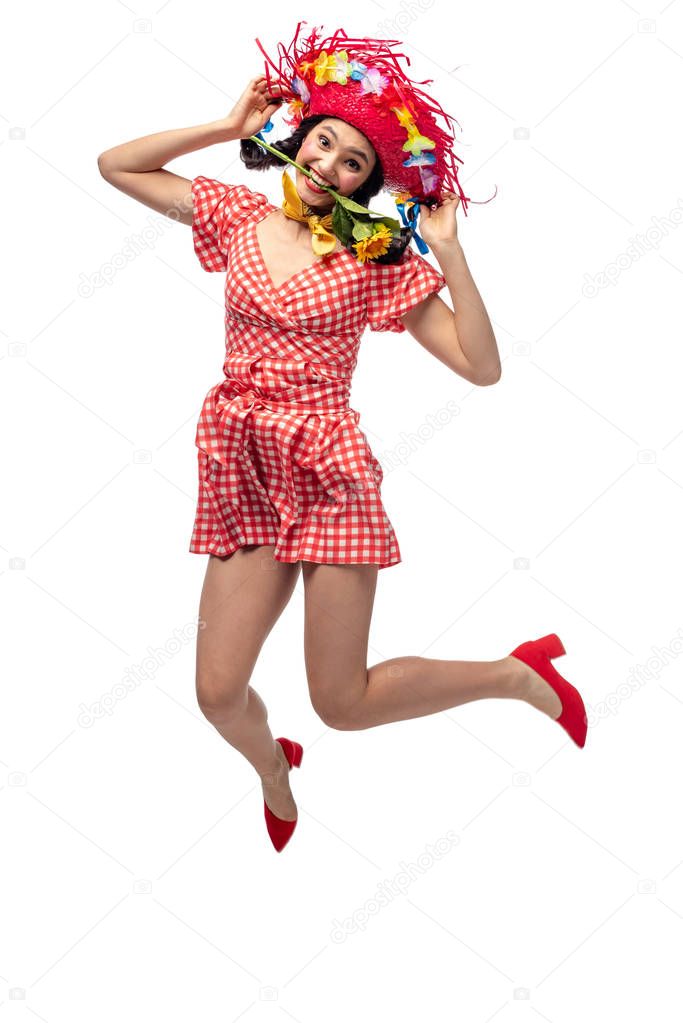 girl in festive clothes and Straw Hat biting sunflower and jumping Isolated On White