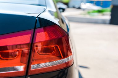 selective focus of red and shiny tail light of black and modern car  clipart